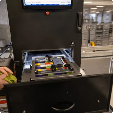 A used iPhone held in a square fixture while hands clean it with a cloth.